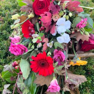 Smuk naturlig bårebuket i røde toner fra Aarstidens Blomster