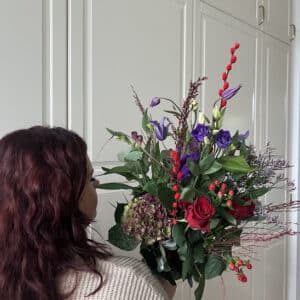 Blå og rød efterårsbuket – rustik buket designet af BlomsterMette Leder du efter en smuk efterårsbuket i blå og røde nuancer? Hos Aarstidens Blomster i Tune finder du denne rustikke efterårsbuket, hvor blåviolette og røde blomster mødes i et spændende farvespil. Buketten er designet af BlomsterMette og passer perfekt som gave eller som en farverig detalje i hjemmet. De blåviolette nuancer forbindes med ro, elegance og kreativitet, mens de røde blomster tilfører varme, energi og liv. Sammen skaber farverne en harmonisk balance mellem det kølige og det varme – et udtryk, der passer smukt til efterårets stemning. En efterårsbuket med personlighed Denne blå og røde efterårsbuket er til dig, der ønsker blomster med karakter. Det rustikke udtryk giver buketten et naturligt og levende præg, mens farvekombinationen gør den til et oplagt valg, når du vil glæde én, du holder af. Send en blomsterhilsen til fødselsdag, som tak, til en værtinde eller blot for at gøre en almindelig dag lidt smukkere. En buket er også en fin måde at vise omtanke på, uden at der behøver at være en særlig anledning. Håndbundet af BlomsterMette & co Hos Aarstidens Blomster bliver blomsterne udvalgt med blik for farver, form og årstid. BlomsterMette og blomsterteamet skaber buketter med personlighed og sans for detaljen fra vores blomsterværksted på Nørregade 7 i Tune. Buketten sammensættes af årstidens tilgængelige blomster. Derfor kan enkelte blomster og detaljer variere fra billedet, mens vi tilstræber at bevare bukettens blåviolette og røde farveudtryk samt dens rustikke stil. Bestil din efterårsbuket online Vil du glæde en modtager med friske blomster eller sætte kulør på dit eget hjem? Bestil din blå og røde efterårsbuket online hos Aarstidens Blomster. Vi tilbyder levering efter de leveringsmuligheder og betingelser, der fremgår af webshoppen. Vælg buketten, skriv eventuelt en personlig hilsen, og lad Aarstidens Blomster hjælpe dig med at sende en blomsterhilsen med varme, farve og omtanke. Aarstidens Blomster – håndbundne blomster med personlighed fra Tune.